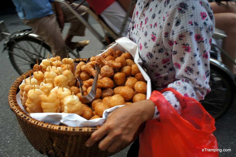 A lady selling freshly baked and fried food on the streets of Hanoi.