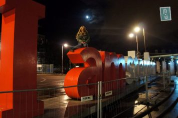 A girl sitting on Amsterdam letters