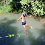 Laotian kid jumps in the river from the bridge