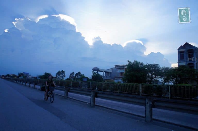 A boy is cycling and there is a beautiful sunrise behind him