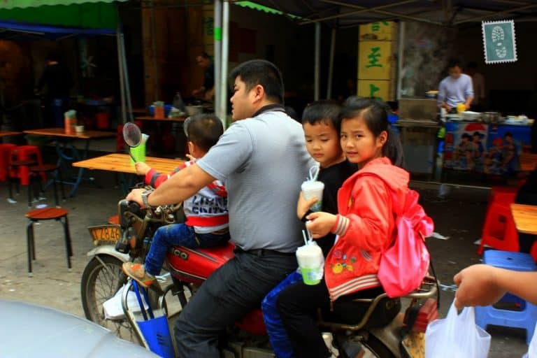 A Chinese family on a bike holding their breakfast