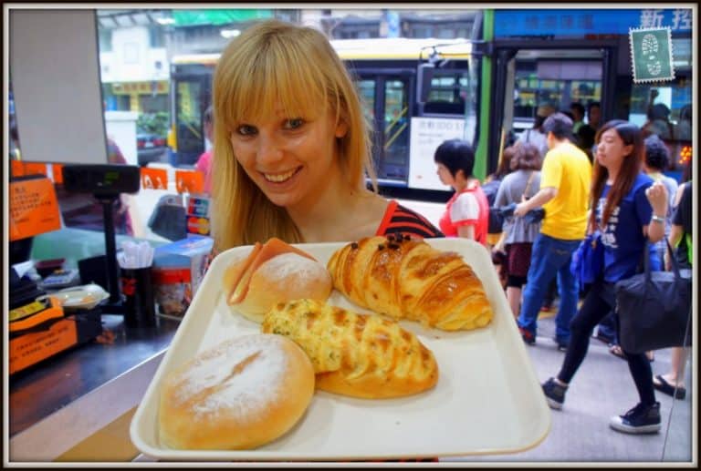 A girl is holding a tray with Chocolate croissant, had bun, garlic bread and mini cheese soft baguette in a bakery in Macau