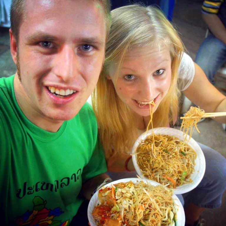 two people are eating pad thai in the street in bangkok