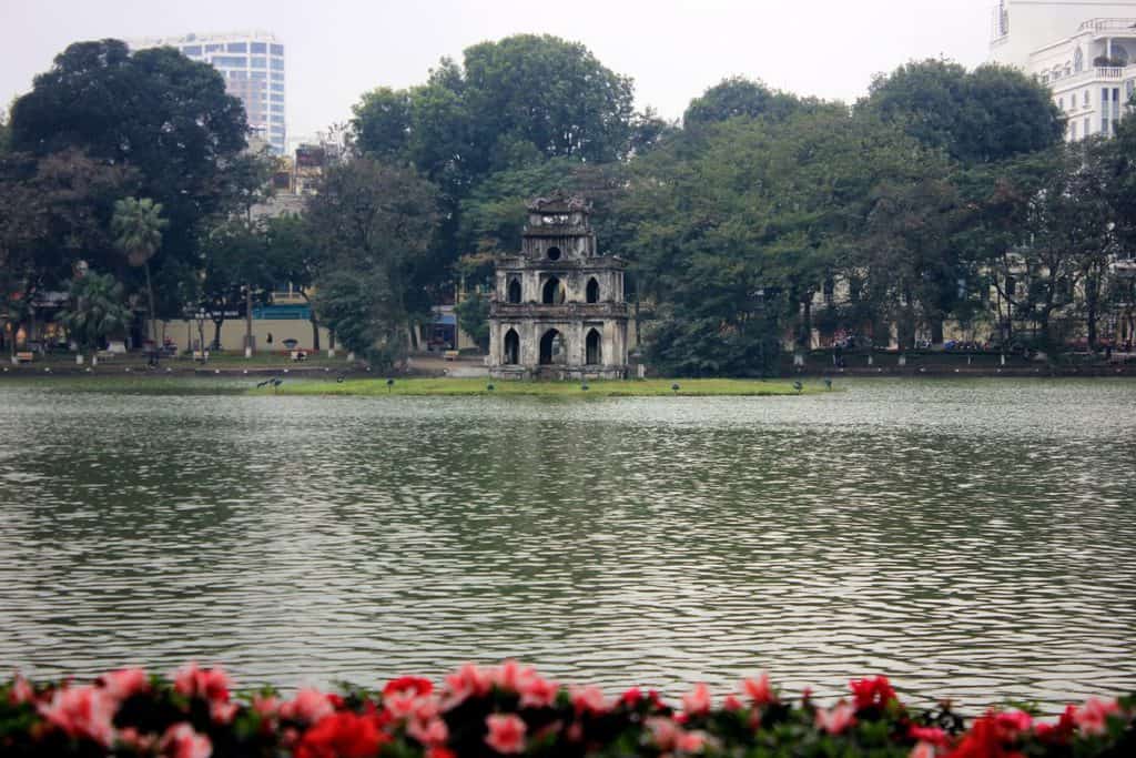 A small island in the middle of the lake with a tower.