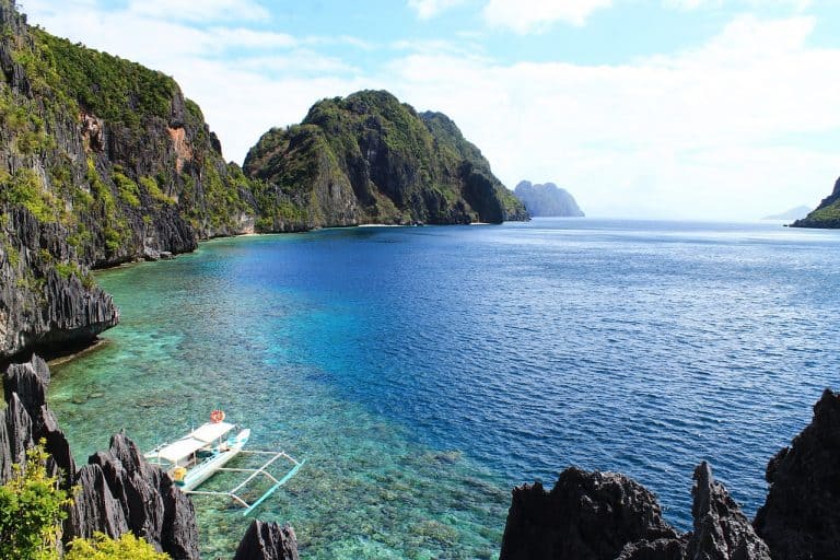 A bay surrounded by cliffs and a a local boat in El Nido.