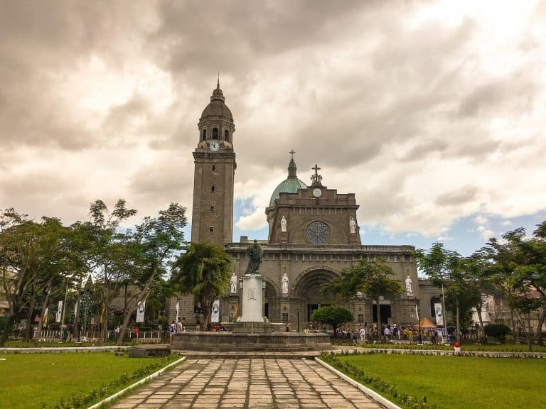 An Intramuros square with a statue and the cathedral in the background.