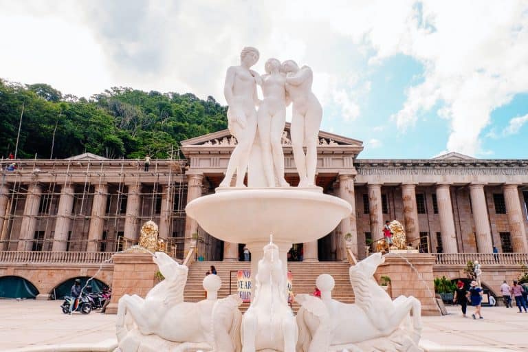 A classical roman-styled temple with a fountain in the front.