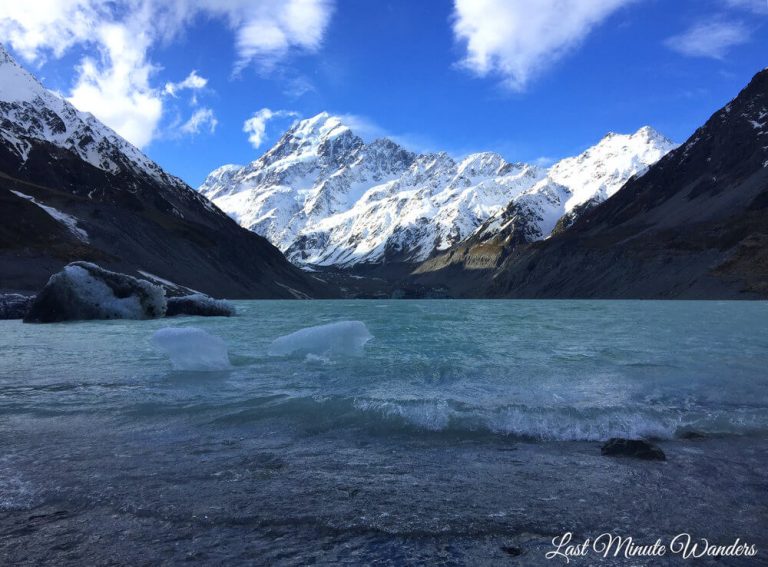 Mountain covered in snow behind blue lake with floating icebergs.