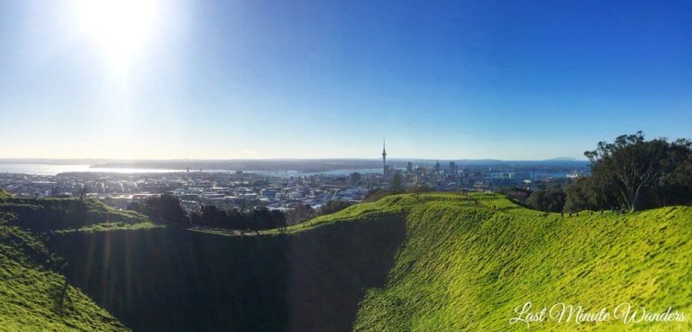 Grassy volcano crater in foreground with Auckland city in the background.